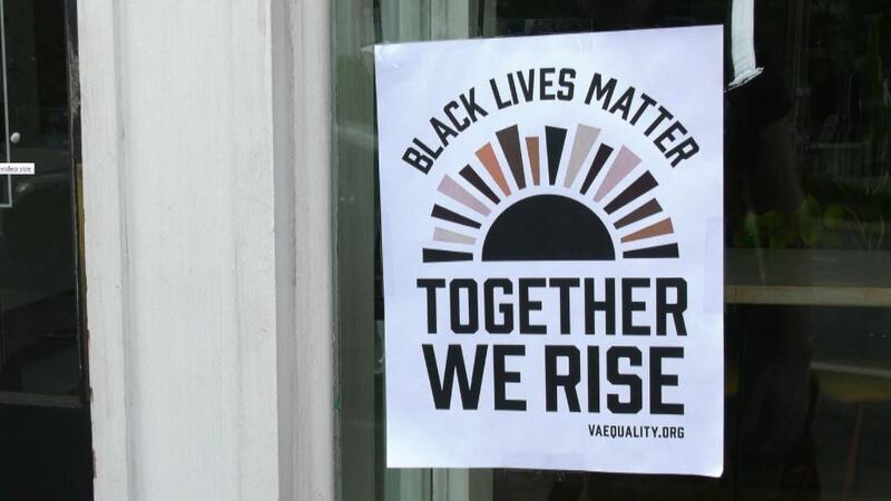 Together We Rise campaign poster hangs in business window in Charlottesville.