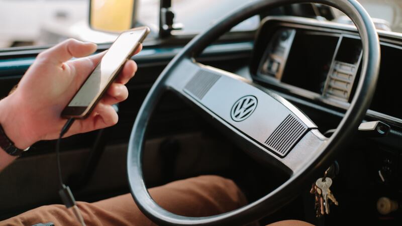 A driver uses a phone while behind the wheel of a car.